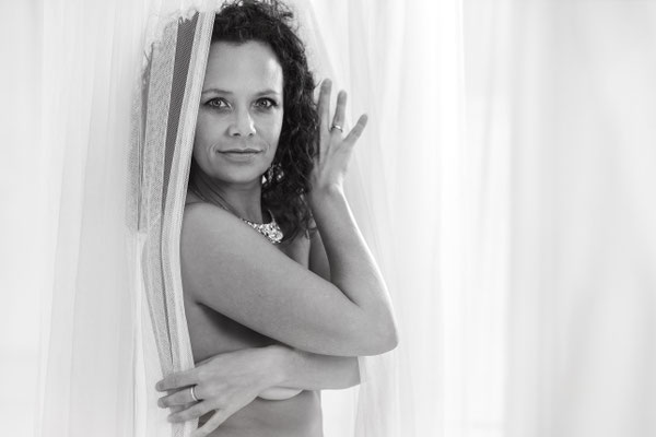 Nackte Frau zwischen Vorhängen beim Aktshooting im Fotostudio in Erlangen. Erotische Fotografie mit künstlerischen Elementen.