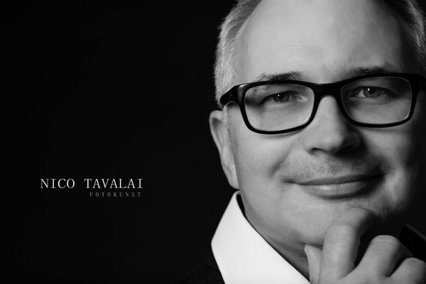 Schwarzweiß-Businessportrait eines Mannes mit Brille, seriöser Ausdruck, Nahaufnahme Gesicht