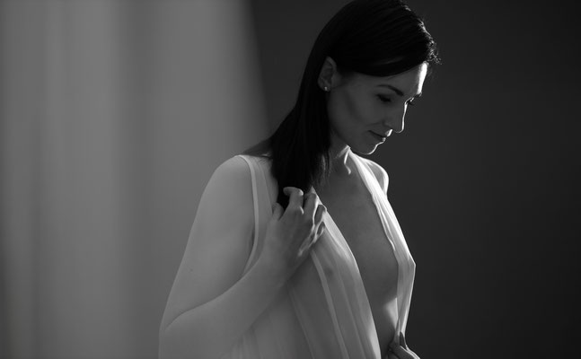 Sinnliches Bild von Frau mit transparenter Bluse durch die man ihre nackten Brüste erahnen kann. Sinnliches Boudoir Shooting.