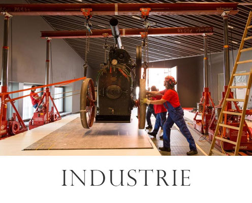 Industriefotografie in Erlangen - Bespielbild: Männer verladen Schwerlastlok mit Krankonstruktion – professionelle Werbefotografie für Unternehmen.