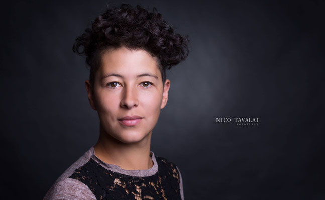 Charakterstarkes Bewerbungsfoto einer Frau mit Locken vor dunklem Hintergrund im Fotostudio