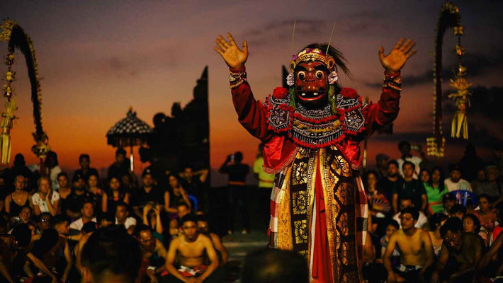 The iconic Kecak dance at Uluwatu Temple, set against a fiery sunset sky.