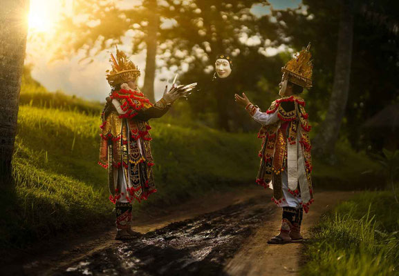Two children dressed in ornate dance costumes, preparing for their performance.