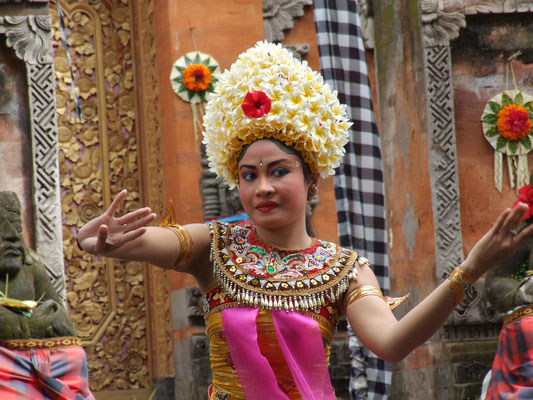 A dancer crowned with frangipani, poised mid-ceremony.