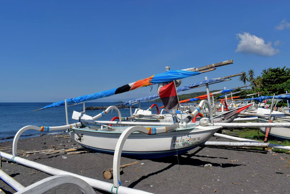 Colorful fishing boats resting on the black sand beach of Jasri in East Bali.