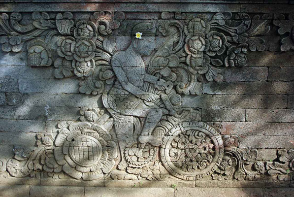 A detailed temple carving depicting a man on a bicycle.
