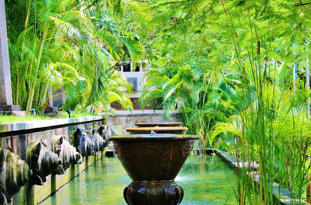 Stone water urns spilling into a tranquil, reflective garden pool.