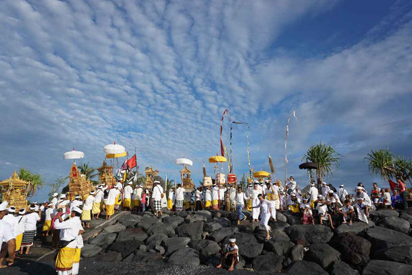 A vibrant Balinese ceremony taking place by the sea.