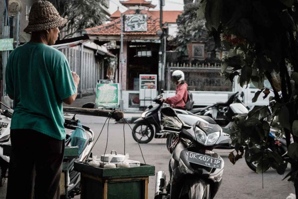 A street vendor offering food along a busy city road.