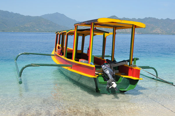 A brightly painted outrigger resting on crystal-clear coastal water.