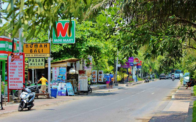 A street scene in Kuta with shops and small businesses lining the road.