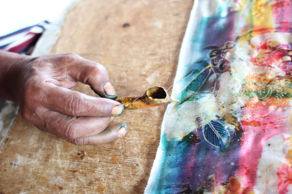 Skillful hands applying hot wax during the traditional batik process.
