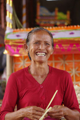 Smiling elder woman in front of her home temple