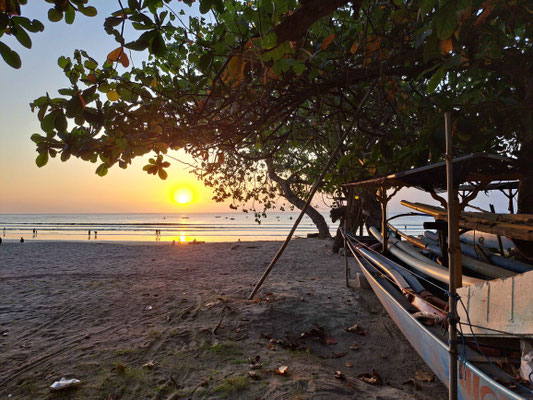 A golden sunset casting warm light over Kuta Beach.