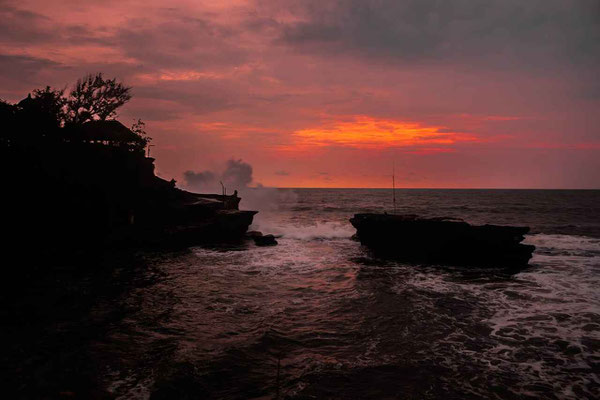 Sunset over the ocean with a temple silhouette.