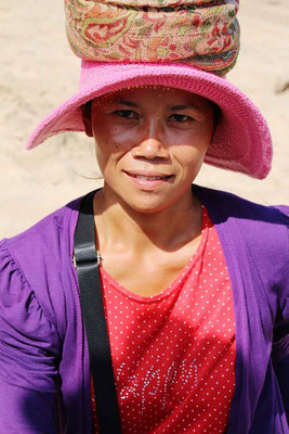 A woman at a local market, helping to carry purchases with a warm smile.