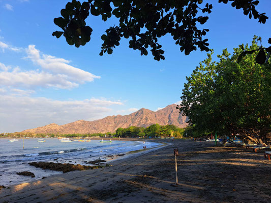 A quiet sandy beach in Pemuteran, framed by distant mountains.
