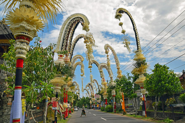 A ceremonial path lined with tall penjor poles and shrines.