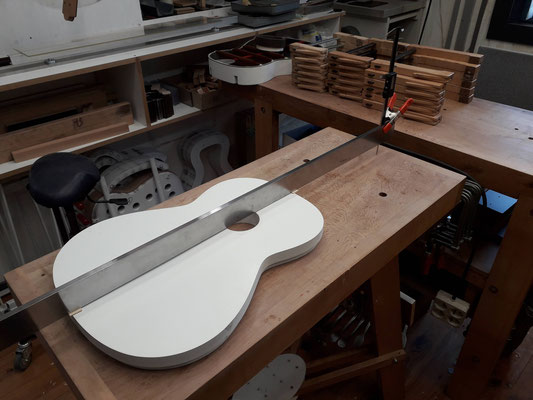 View on the workbench of the soundboard mold and straightedge for validating the neck set angle