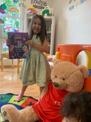 Child reading confidently with the Custom Kids mascot, Zilla, during an English lesson in Ehrendingen.