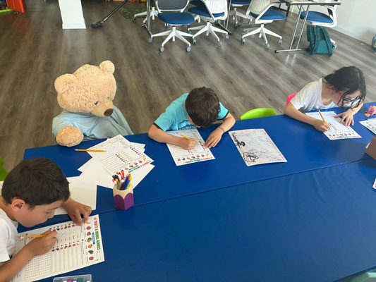 Children practising reading and writing while the Custom Kids mascot, Zilla, joins the lesson.