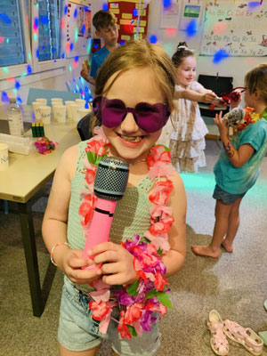 Child posing with a microphone and heart shaped sunglasses at a Custom Kids Pizza Disco Party.