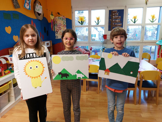 Children proudly showing their completed art projects during a Custom Kids English class.