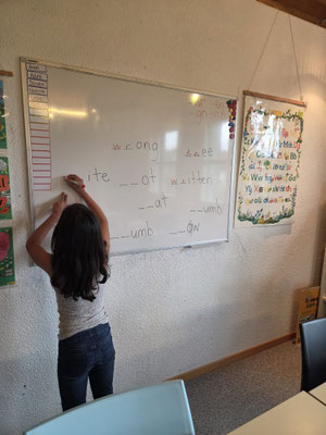 Child building confidence by writing on the whiteboard during a Custom Kids English lesson.