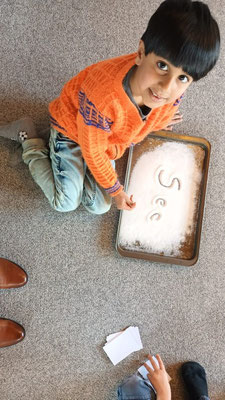 Children practising writing words in salt
