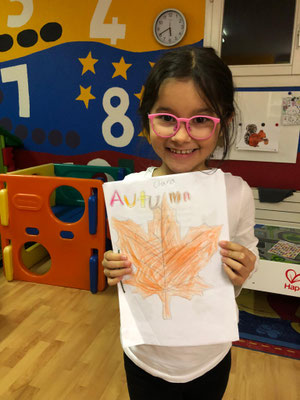Child proudly showing a completed writing project in a Reading & Writing class