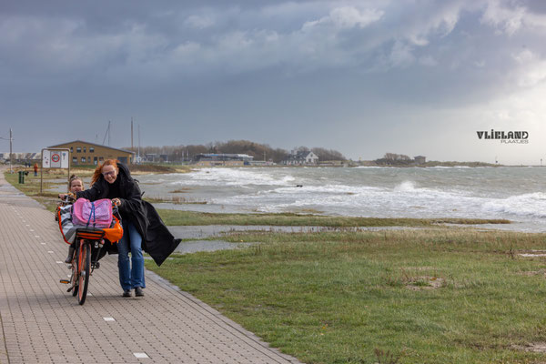 Fietser loopt met Harde wind en Hoog Water Havenweg-oktober 2025