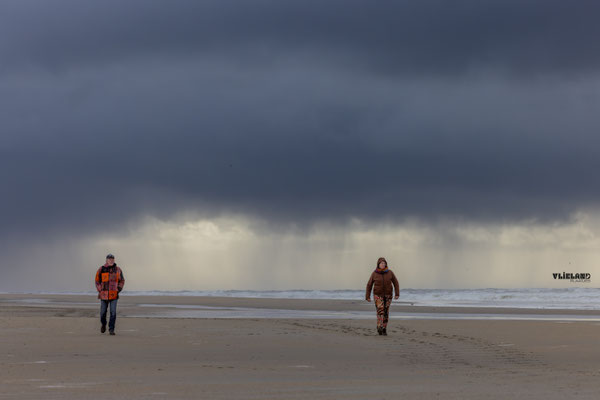 Wandelaars onder donkere buienlucht, maart 2026