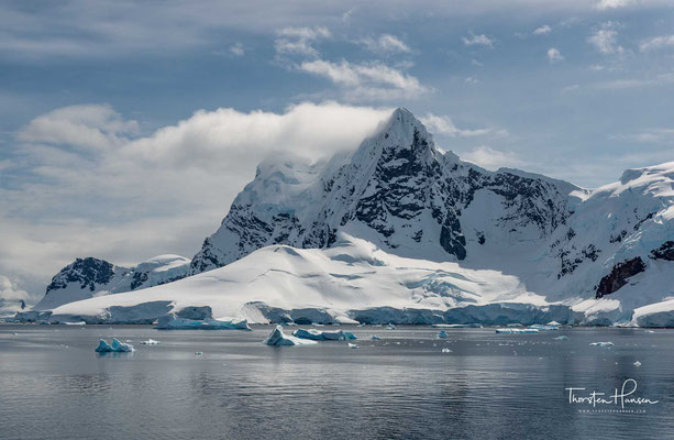 Die Gletscher und Klippen spiegeln sich in den stillen Wasserflächen am südlichen Ende des Kanals. Wenn Eisberge die Weiterfahrt nach Süden blockieren, sind die Kreuzfahrtschiffe gezwungen umzukehren und die Booth-Insel zu umrunden, um die Petermann-Insel