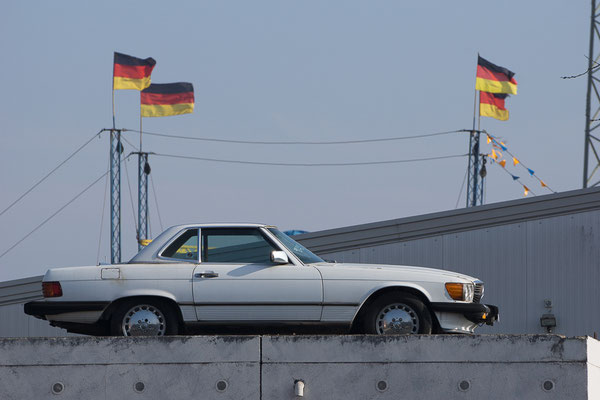 Mercedes Sportwagen mit an Masten wehenden Deutschlandfahnen im Hintergrund.