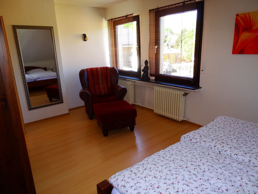 Schlafzimmer mit gemütlichem Sessel und Leselampe
