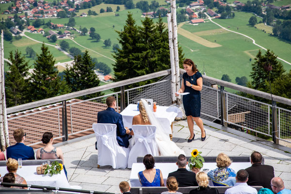 Eine Hochzeitsgesellschaft bei einer freien Bergtrauung mit Blick ins Tal.