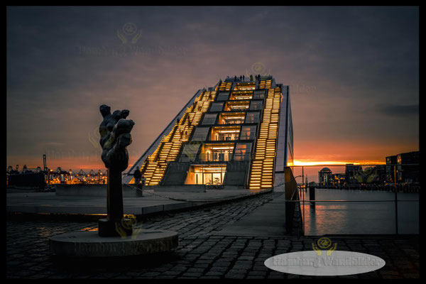 ein sonnenuntergang an der statue am dockland hamburg wandbilder