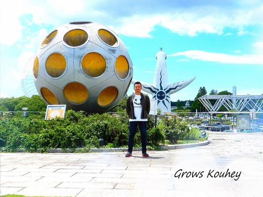 大阪のゲイマッサージGrows（グローズ）の男性セラピストKouhey（コウヘイ）。万博記念公園の太陽の塔とオブジェを背景にした紹介画像。北区・梅田・中崎町エリア。