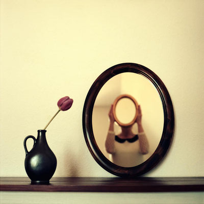 Manuela Deigert Mittelformat Selbstportrait mit einem Spiegel vorm Gesicht und Reflexion von einem anderen Spiegel an der Wand