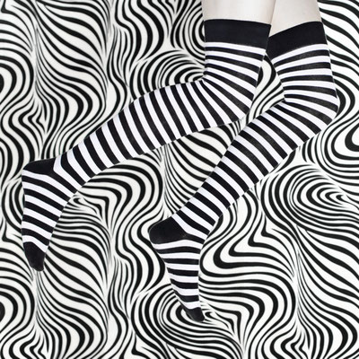Manuela Deigert Projekte Selbstportrait Beine mit schwarzweiß gestreiften Strümpfen und psychedelisch grafischem Hintergrund