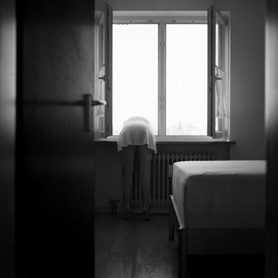 Manuela Deigert Mittelformat schwarzweißes Selbstportrait in einem Zimmer mit Fenster, aus dem ich mich mit dem Oberkörper herauslehne