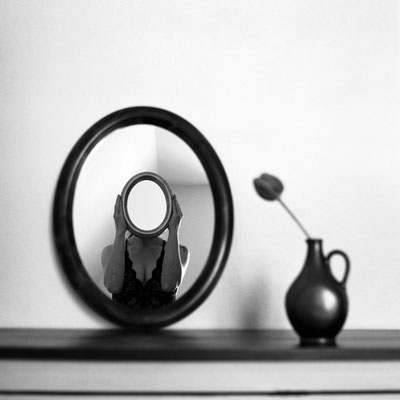 Manuela Deigert Mittelformat Selbstportrait mit einem Spiegel vorm Gesicht und Reflexion von einem anderen Spiegel