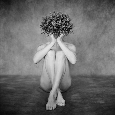 Manuela Deigert Mittelformat Nude Selbstportrait mit Pflanze vor dem Gesicht in sitzender Pose