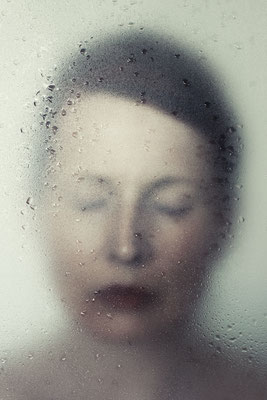 Manuela Deigert Projekte Melancholisches Selbstportrait mit verschlossenen Augen hinter einer Scheibe mit Wassertropfen