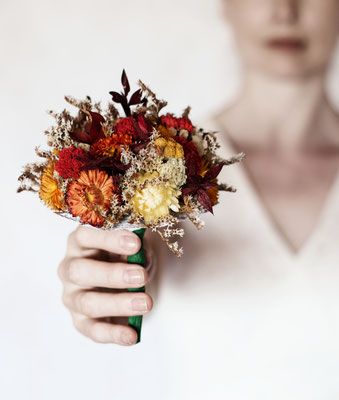 Manuela Deigert Projekte Frau hält einen Blumenstrauß aus getrockneten Strohblumen in der Hand