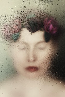 Manuela Deigert Fotokunst Start, Künstlerisches melancholisches Selbstportrait mit verschlossenen Augen und Blumenhaarkranz hinter einer Scheibe mit Wassertropfen
