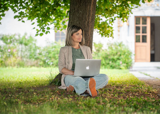 Businessfrau, die unter einer Linde sitzt, und arbeitet.