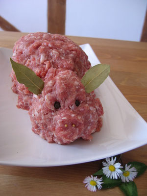 Gehacktes in Form eines Schweins, dekoriert mit Blättern und Gänseblümchen