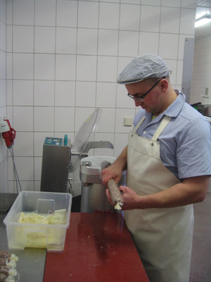 Ein Mann füllt Wurstmasse in eine Verpackung