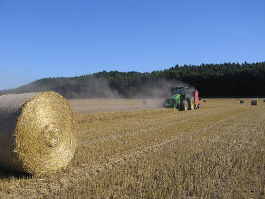 Ein traktor auf einem Feld mit Ballen